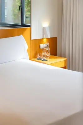 a hotel room with a bedroom with a bed and a table at Hotel SB Icaria in Barcelona