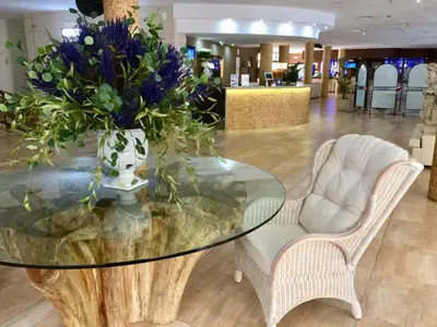 a glass table with a vase of flowers in a lobby at Aparthotel Miami Park in Calella