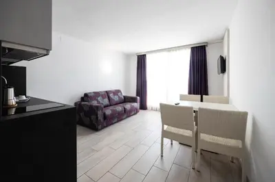 a kitchen and a living room with a table and chairs at Aparthotel Miami Park in Calella