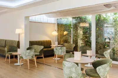 a waiting room with tables and chairs and a large window at DWO Les Palmeres in Calella
