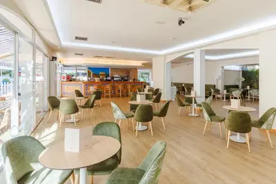 a dining room with tables and chairs and windows at DWO Les Palmeres in Calella