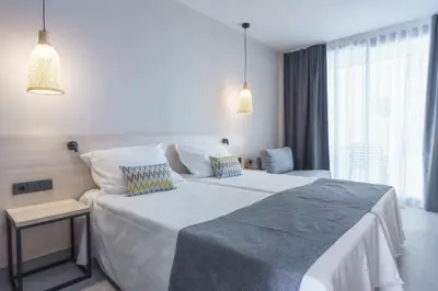 a bedroom with a large white bed and a chair at DWO Les Palmeres in Calella
