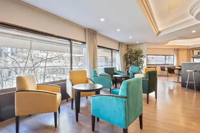 a waiting room with chairs and tables and windows at Acta Antibes in Barcelona