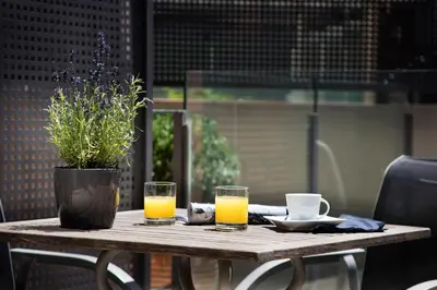 a wooden table with two glasses of orange juice at Casa Elliot Hotel in Barcelona