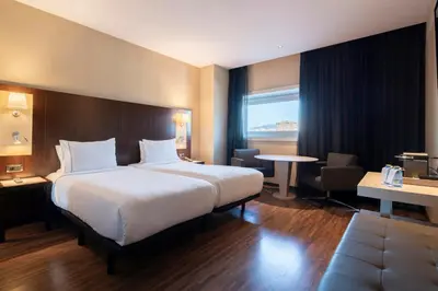 a hotel room with a large bed and a table at Leonardo Royal Hotel Barcelona Forum in Barcelona