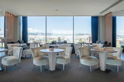 a restaurant with tables and chairs and large windows at Leonardo Royal Hotel Barcelona Forum in Barcelona
