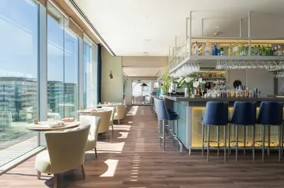a restaurant with a bar with blue chairs and tables at Leonardo Royal Hotel Barcelona Forum in Barcelona