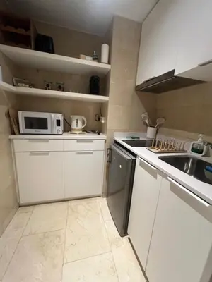 a white kitchen with a sink and a microwave at Precioso y tranquilo apartamento zona alta Diagonal Barcelona in Barcelona