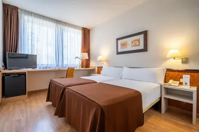 a hotel room with a bed and a desk and a television at Hotel Glòries in Barcelona