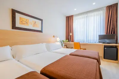 a hotel room with two beds and a television at Hotel Glòries in Barcelona