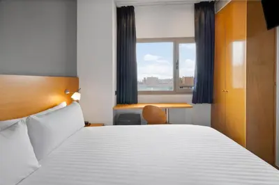 a bedroom with a bed and a desk and a window at B&B HOTEL Barcelona Mollet Porta de Gallecs in Mollet del Vallès
