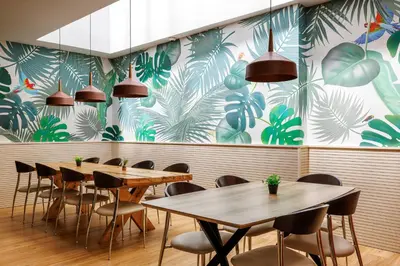 a restaurant with wooden tables and chairs and a mural at Hotel Ronda Lesseps in Barcelona