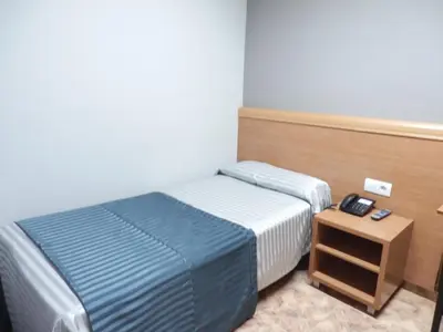 a small bedroom with a bed and a night stand at Hotel Inglés in Barcelona