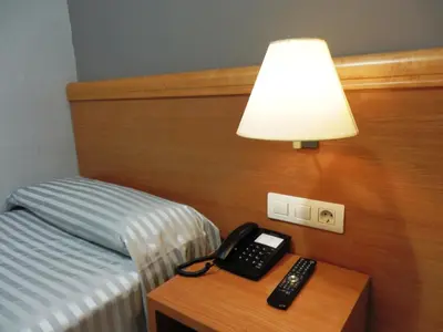 a lamp and a telephone on a table next to a bed at Hotel Inglés in Barcelona