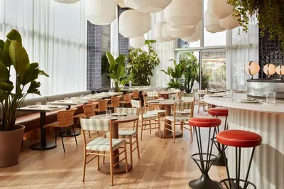 a restaurant with tables and chairs and potted plants at The Hoxton, Poblenou in Barcelona
