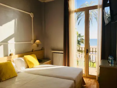 two beds in a room with a view of the ocean at Hotel Celimar in Sitges