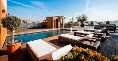 a rooftop patio with chairs and a pool on a building at Hotel Urpí in Sabadell