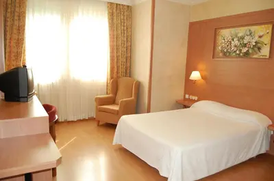 a hotel room with a bed and a chair at Hotel Urpí in Sabadell