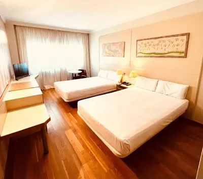 a hotel room with two beds and a window at Hotel Urpí in Sabadell