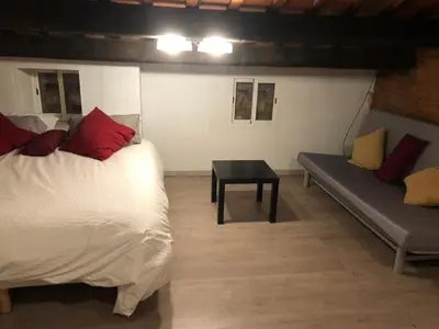 a bedroom with a bed and a couch and a table at Charming house next to the sea and Barcelona for 6 in Badalona