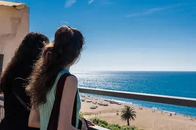 two women looking out at the ocean from a balcony at Espanya - 30º hotels in Calella