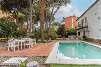 a swimming pool with a table and chairs next to a house at Canela Homes COSTA CA NOSTRA in Gavà