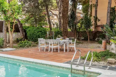a dining table and chairs next to a swimming pool at Canela Homes COSTA CA NOSTRA in Gavà