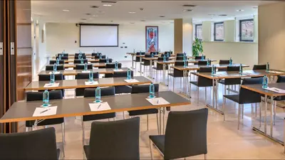 a lecture hall with tables and chairs and a screen at Gran Hotel Rey Don Jaime in Castelldefels