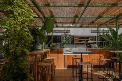 a restaurant with wooden tables and stools in a room with plants at Hotel Pulitzer Barcelona in Barcelona