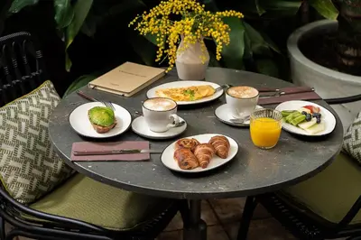a table with plates of food and cups of coffee at Hotel Pulitzer Barcelona in Barcelona