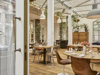 a restaurant with wooden tables and chairs and windows at Hotel Pulitzer Barcelona in Barcelona