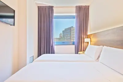 two beds in a hotel room with a window at Hotel Acta Azul Barcelona in Barcelona