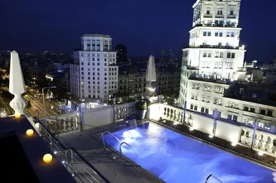a view of a building with a pool at night at El Avenida Palace in Barcelona