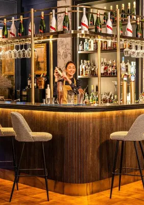 a woman is standing behind a bar at El Avenida Palace in Barcelona