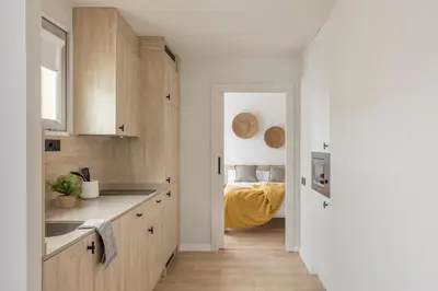 a kitchen with wooden cabinets and a bed in the background at Líbere Barcelona Sant Antoni in Barcelona