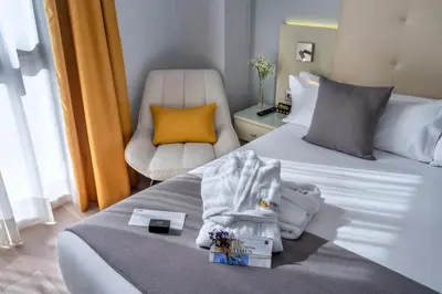 a hotel room with two beds and a chair at Hotel SERHS Del Port in Barcelona