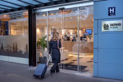 a woman pulling a suitcase in front of a store at Hotel SERHS Del Port in Barcelona