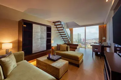 a living room with a staircase and a couch and chairs at Hyatt Regency Barcelona Tower in Hospitalet de Llobregat