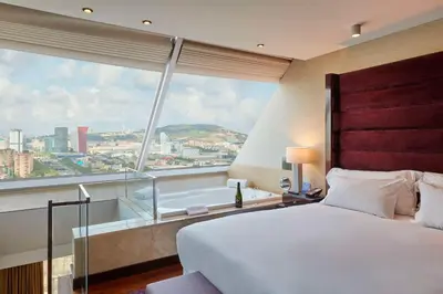 a bedroom with a large bed and a large window at Hyatt Regency Barcelona Tower in Hospitalet de Llobregat