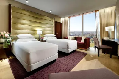 a hotel room with two beds and a desk at Hyatt Regency Barcelona Tower in Hospitalet de Llobregat