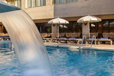 a water slide in a pool with chairs and umbrellas at htop Amaika & SPA 4Sup - Adults Only #htopBliss in Calella