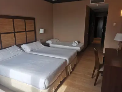two beds in a hotel room with a table and chairs at Aparthotel Attica 21 Vallés in Sabadell