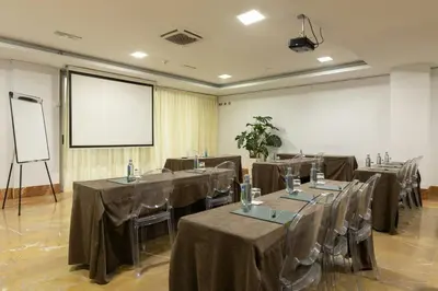 a conference room with tables and chairs and a screen at Sercotel Kalma Sitges in Sitges