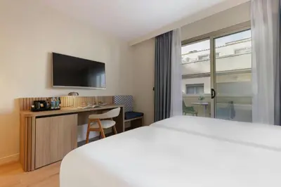 a hotel room with a bed and a desk and a tv at Sercotel Kalma Sitges in Sitges