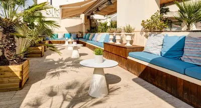 a patio with couches and tables and plants at Sercotel Kalma Sitges in Sitges