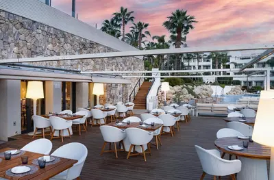 a restaurant with white chairs and tables on a deck at Eurostars Sitges in Sitges