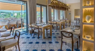 a dining room with tables and chairs and windows at Eurostars Sitges in Sitges