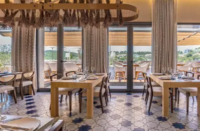 a restaurant with tables and chairs and windows at Eurostars Sitges in Sitges