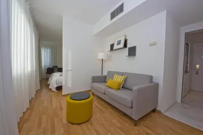 a living room with a couch and a yellow stool at Aparthotel Atenea Valles in Granollers