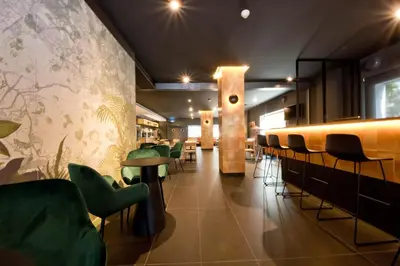 a restaurant with green chairs and a bar at Aparthotel Atenea Valles in Granollers